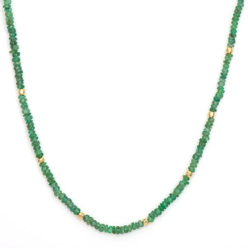 The Delicate Emerald Beaded Chain 18 from Three Stories Jewelry features small green beads with occasional gold accents in a single strand, enhanced by charms forming an exquisite circular design.