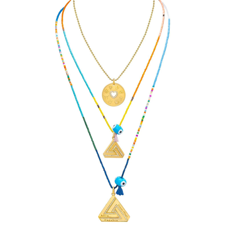 Aaron Bashas Large Abracadabra Triangle Series 5 collection features three vibrant necklaces that radiate personal empowerment. The top necklace boasts a gold engraved pendant, while the middle and bottom pieces display blue evil eye beads and gold triangular pendants with blue tassels.