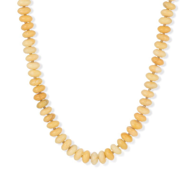 A close-up of the Adina Reyter Yellow Jade Gemstone Necklace, featuring rounded, disc-shaped yellow and light brown beads arranged in a graduated pattern on a white background.