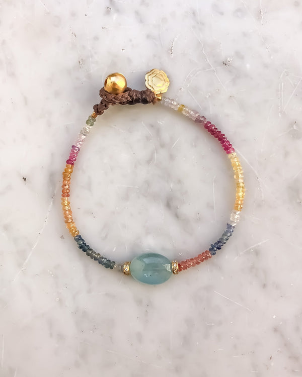 The ETTORE Bracelet by Bohemian Rhapsodie Paris features a vibrant mix of pink, orange, yellow, and turquoise beads against a white marble background. A central blue bead is flanked by silver gold-plated accents.