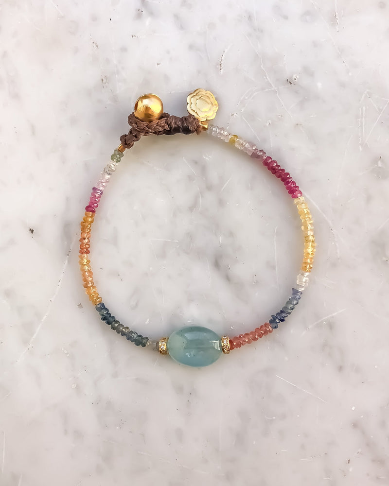 The ETTORE Bracelet by Bohemian Rhapsodie Paris features a vibrant mix of pink, orange, yellow, and turquoise beads against a white marble background. A central blue bead is flanked by silver gold-plated accents.