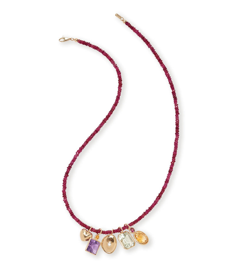 The Tiny Beaded 14k Gold Necklace in Ruby by Lizzie Fortunato features deep red ruby beads and five 14k gold charms, each set with unique gemstones in assorted shapes and colors, elegantly arranged at the center.