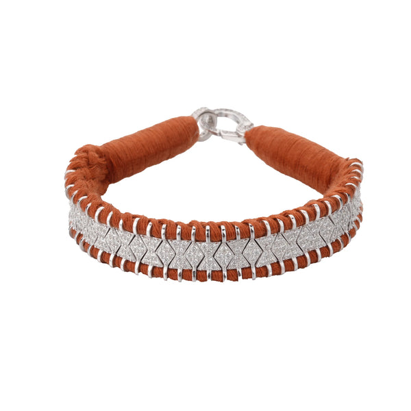 The Janeiro Hazelnut Bracelet by Van Den Abeele is a bohemian-style piece featuring a vibrant orange woven fabric cord and interlocking silver chevrons with a textured pattern, completed with a secure clasp closure.