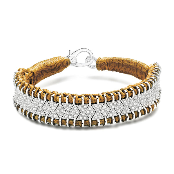 The Van Den Abeele Janeiro Ochre Bracelet is handmade with a brown, rope-like texture and interwoven with a silver metal band. It features a zigzag pattern adorned with small clear stones, embodying bohemian glamour, and is secured elegantly by a metal clasp.