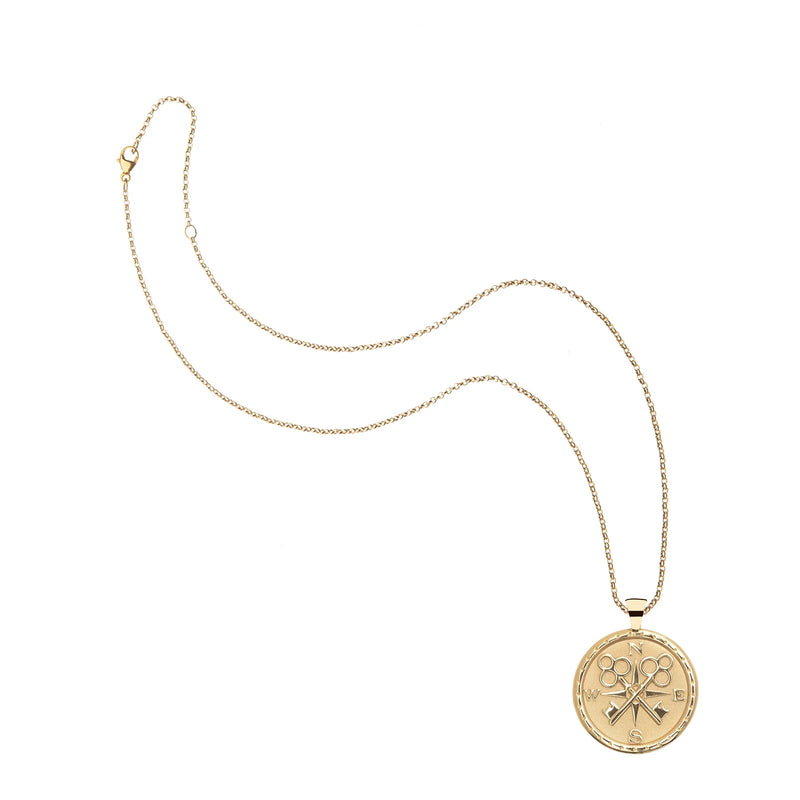 The Jane Win Forever Coin Pendant is a gold-plated necklace featuring a round charm embossed with scissors and combs, shown on a white background.