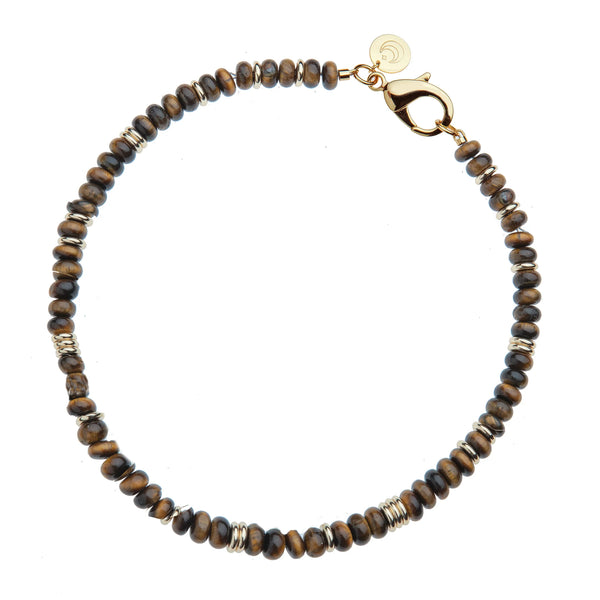 The Gumdrop Beaded Necklace in Tiger’s Eye by Jane Win features round brown and black tiger’s eye beads, silver spacers, a gold lobster clasp, and a small gold charm.