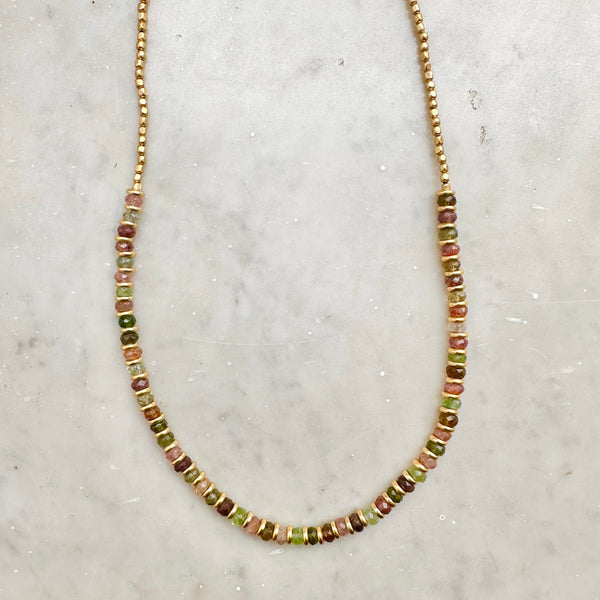 The CHOKER ELLIE by Bohemian Rhapsodie Paris is a beaded necklace showcasing a vibrant mix of colorful beads, with earthy hues of green, brown, and pink contrasted against a light marble backdrop. Ideal for meditation, its multicolored tourmaline adds harmony and balance to your style.