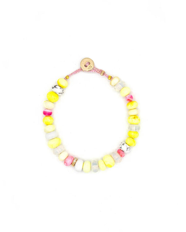 The Scosha Candy Gem Bracelet in Lemonade features chunky yellow, white, pink, and marbled gemstone beads on a pink cord with a round tan button clasp. The bracelet is displayed in a loose circle against a white background.