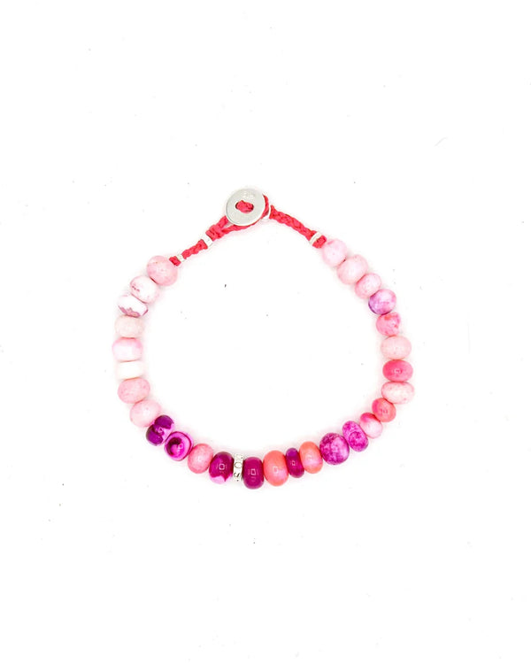 The Scosha Candy Gem Bracelet in Gelato, featuring pink and magenta beads with ruby accents, a red cord, and a round silver clasp, is displayed on a white background.