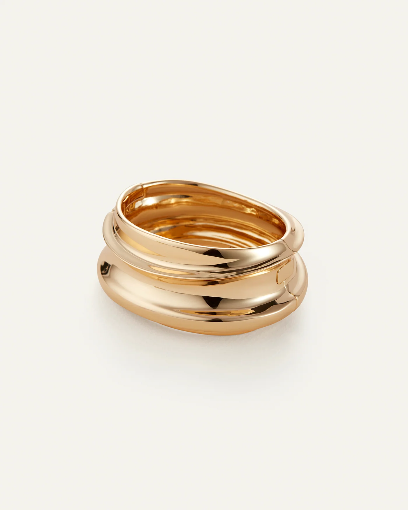 The Mega Lennon Bangle by Jenny Bird features a shiny, chunky gold design with smooth, rounded curves—photographed on an off-white background and perfect for pairing with your favorite statement rings or custom bracelets.