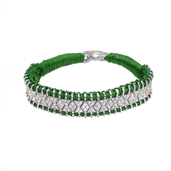 Explore the Janeiro Grass bracelet by Van Den Abeele, a handcrafted silver piece adorned with a sparkling diamond strip and bordered by intricate green weaving. It features a textured finish and secures elegantly with a clasp.