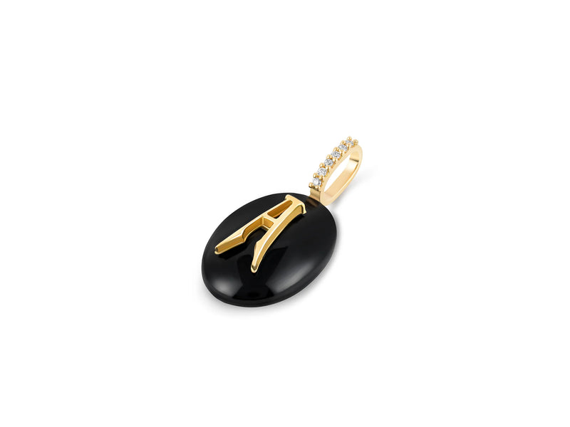 The Small Oval Cabochon Monogram Charm by Kate Collins Jewelry is a gold pendant with a black oval base and a golden H design. The loop, inspired by Kate Collins Charms, features sparkling stones and elegantly hangs from a charm necklace with an easy-to-use gold extender clasp.