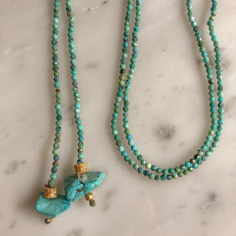 The KEVIN Lariat by Bohemian Rhapsodie Paris is displayed on a marble surface. It features small round turquoise beads, gold-plated accents, and larger irregular turquoise stones near the clasp, with pyrite hints that enhance its elegant design.