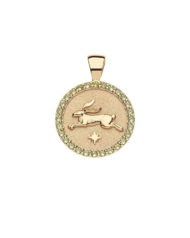 The LUCKY Rabbit JW Small Embellished Pendant Coin by Jane Win, featuring a leaping rabbit with an engraved star and bordered by small green gemstones, is a charming gold symbol of good fortune.