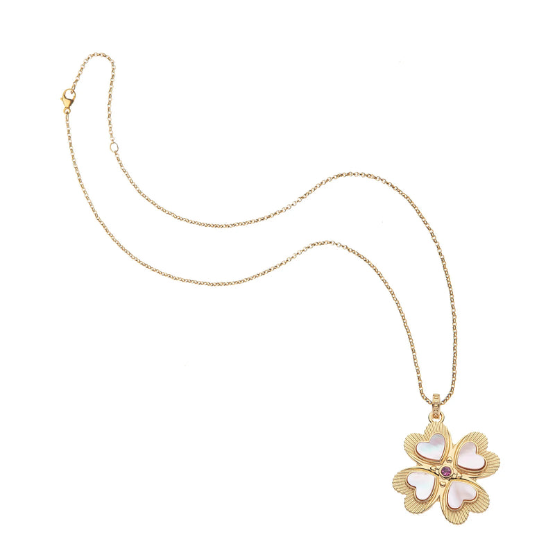 The Lucky in Love Clover Pendant with Pink Shell by Jane Win is a gold necklace featuring a four-leaf clover pendant with heart-shaped petals and a central pink tourmaline, offering an enchanting touch of elegance.