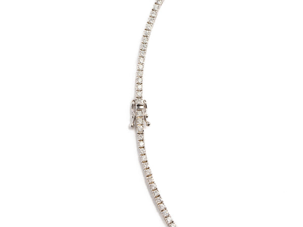 A delicate Monarch Market Lab Grown Tennis Necklace displayed on a white background features a continuous line of small, sparkling diamonds set in a white metal, connected by an elegant clasp.