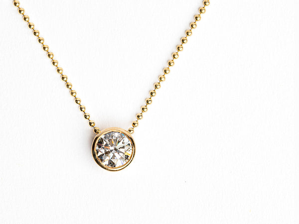 The Monarch Market Lab Grown Large Gold Bezel Necklace showcases a small, round diamond pendant set in gold against a white background.