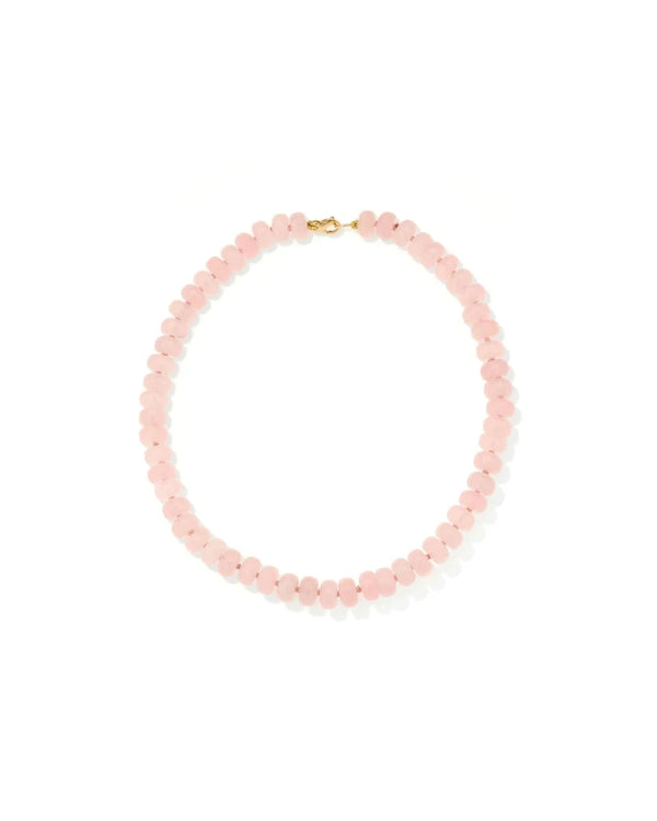 The Spring into Pink Gemstone Necklace by Adina Reyter showcases round, pale pink rose quartz beads and a small gold clasp, arranged in a circle on a white background. This limited edition piece exudes feminine elegance.