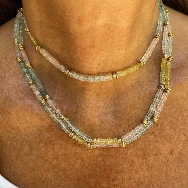 Close-up of a neck wearing Bohemian Rhapsodie Pariss NOTO, a Baroque-style necklace featuring double layers of translucent pastel beads in blue, pink, and yellow with 18K gold spacers. The background is the persons skin.