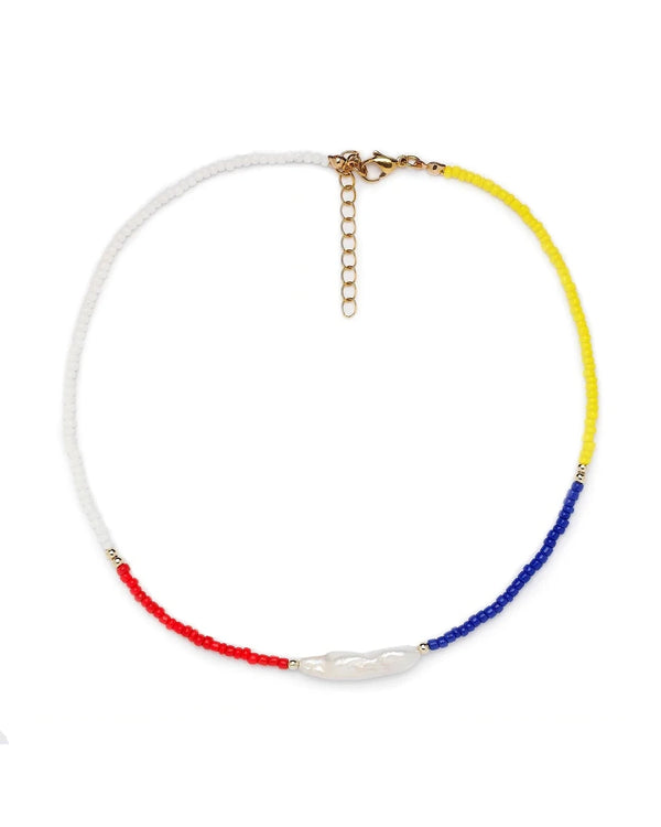 The Raven Pearl Beaded Choker by Oiya features white, red, blue, and yellow beads with a central mini red lapis stone and a gold adjustable clasp.