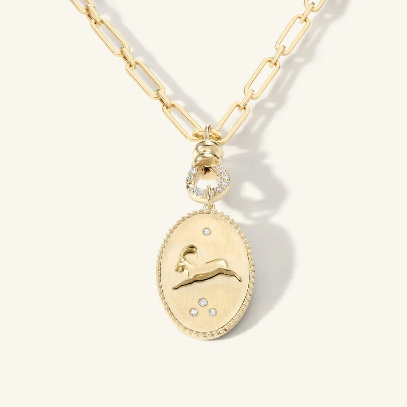 The Pave Diamond Swivel by zahava is a stunning gold necklace featuring a chain link design, an oval pendant with a stylized Capricorn goat in relief, and embellished pavé diamonds. Its 10k gold swivel connector adds elegance to any ensemble.