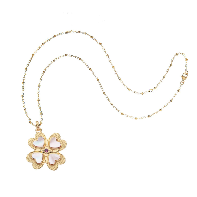 The Lucky in Love Clover Pendant by Jane Win features a gold-plated sterling silver chain with a heart-adorned clover and a central pink tourmaline gem, blending elegance and charm.