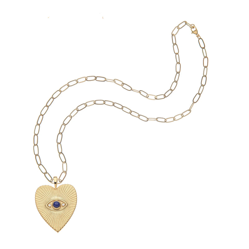 The Jane Win PROTECT Eye On Your Heart Pendant is a gold chain necklace with elongated links, featuring a heart charm engraved with lines and a vivid blue evil eye at its center.