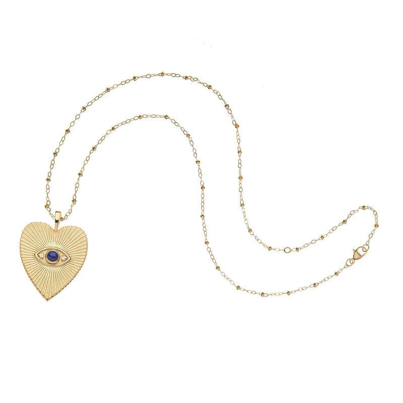 Jane Wins PROTECT Eye On Your Heart Pendant is a gold necklace with a fine chain and a textured heart pendant, featuring an embossed blue-centered evil eye in the middle.