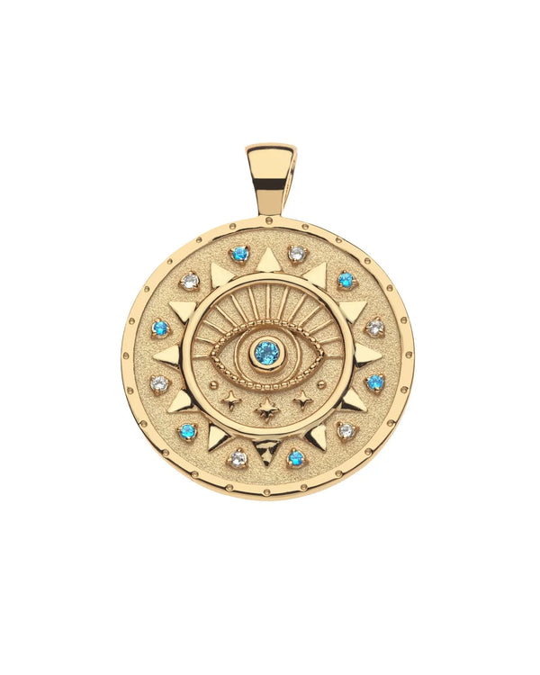 The PROTECT Ancient Eye Pendant by Jane Win is a round gold pendant featuring a raised eye, radiating lines, sparkling stones, and blue sapphires along the edge. This striking piece is available in limited edition.