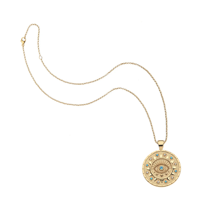 The PROTECT Ancient Eye Pendant by Jane Win is a limited edition gold chain necklace featuring a bold round evil eye centerpiece, accented with blue sapphires and clear gemstones in a striking circular design.