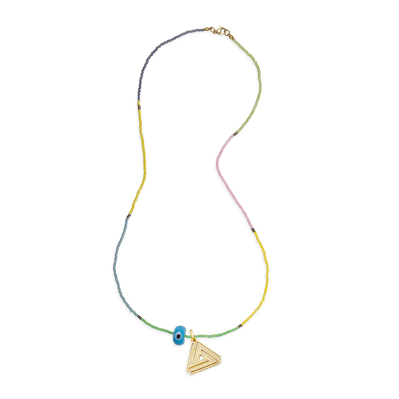 The Sandy Eye Necklace by Aaron Basha features a multicolored beaded string in green, yellow, and pink, with a gold triangular pendant and a ceramic eye amulet that has a small blue bead with a white eye design.