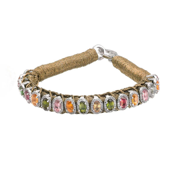 The Rio Brass bracelet by Van Den Abeele features oval gemstones in pink, orange, and green set in silver. Handmade with brown cord detail for added texture, it closes with a sleek silver clasp.