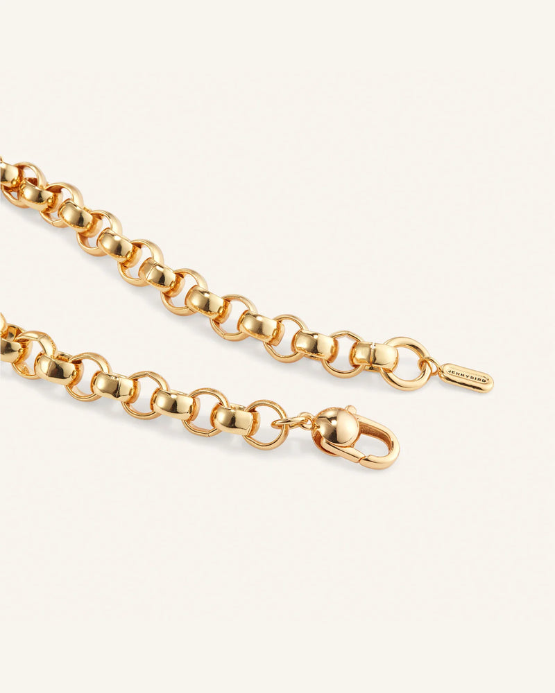 The Rodin Chain by Jenny Bird, a high-polish gold rolo chain with interlocking circular links, is showcased against a light background. It includes a small clasp and an engraved tiny rectangular tag, adding elegance to the piece.