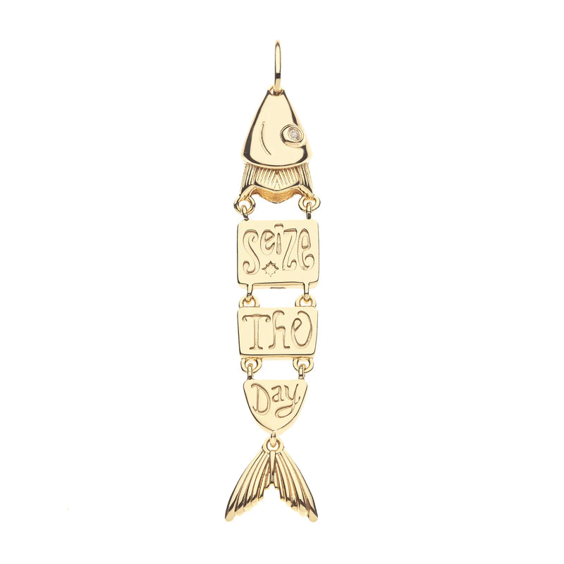 The Jane Win STRONG Carpe Diem Fish Pendant is a vintage-style charm shaped like a gold fish, with segmented parts spelling “Seize The Day” and fin-shaped tail, plus a top loop for easy attachment.