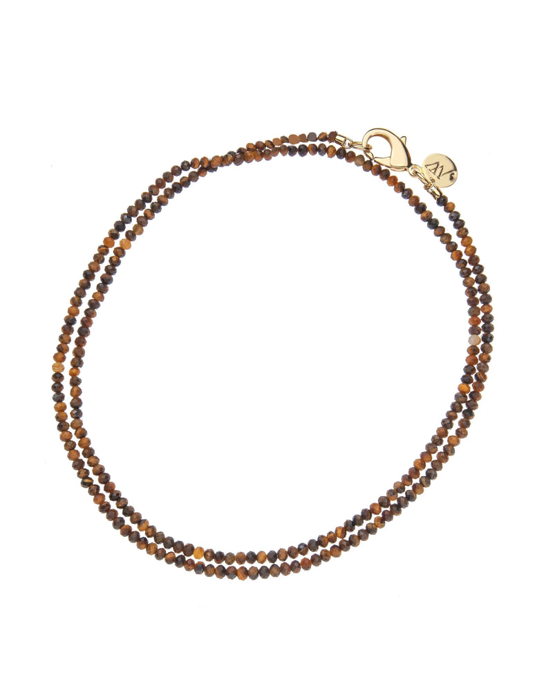 The Jane Win Double Wrap Diamond Cut Beaded Necklace in Tiger's Eye features small, round tiger’s eye beads and a diamond cut design, finished with a gold plated clasp and a round gold charm.