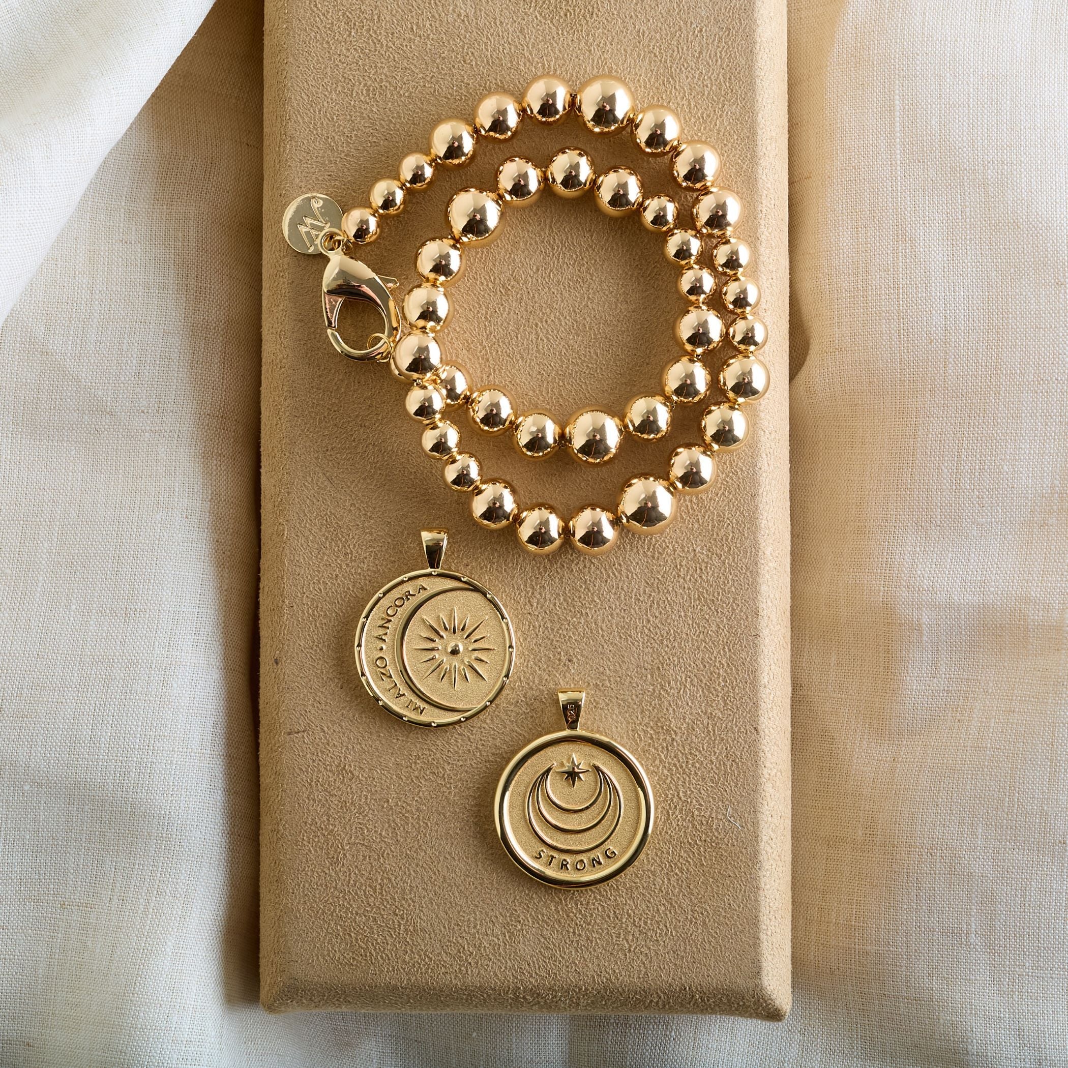 The Sun Reflection Beaded Necklace by Jane Win is displayed on a beige fabric-covered box, set against a soft, off-white fabric background.