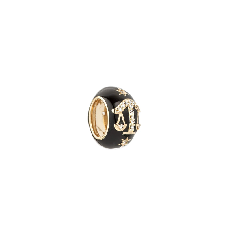 The Adina Reyter Zodiac Ceramic + Diamond Libra Big Bead is a 14k yellow gold ring with a wide glossy black band, gold stars, a diamond-encrusted Libra charm, and a polished gold interior.
