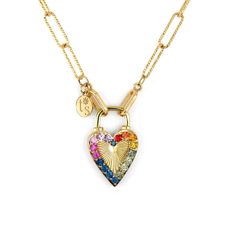 The Three Stories Jewelry Open Diamond Cut Paperclip Chain 18 in 14k gold showcases a heart-shaped padlock pendant with multicolored gemstones in a rainbow pattern, along with a small round charm engraved with initials.