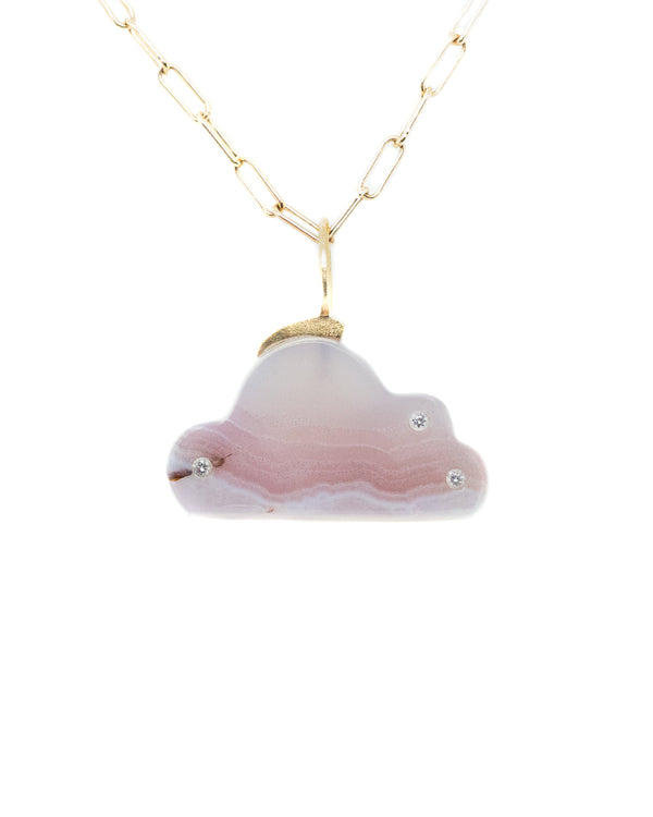 The Agate Cloud Charm by Karen Luvaas is a gold chain necklace with a pink cloud-shaped pendant, adorned with small gemstones and a crescent moon gold accent.