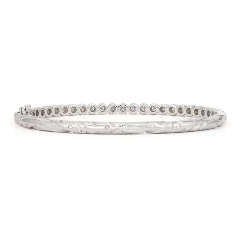 The Blended Hammered Diamond Bezel Bangle by Three Stories Jewelry is an elegant sterling silver bracelet featuring a subtle twisted design with small, evenly spaced round details, giving it a delicately crafted diamond bangle allure.