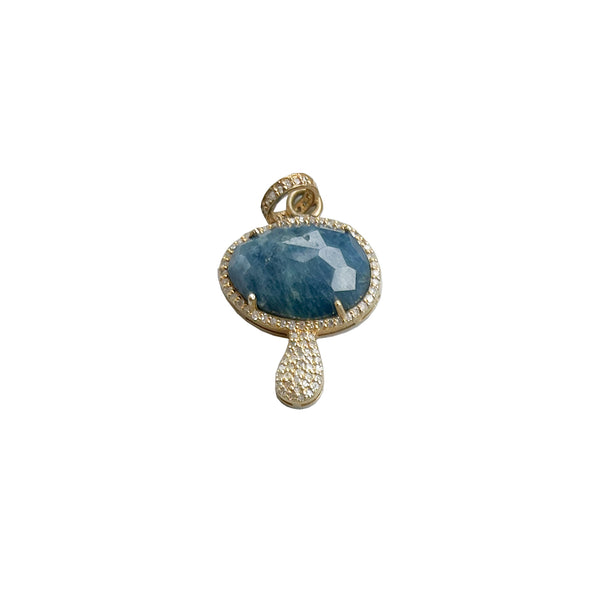 The Woods presents the Blue Diamond Mushroom pendant, showcasing a large faceted blue apatite stone encircled by whimsical pavé diamonds, set in gold with a textured handle-like design and a loop for a chain.