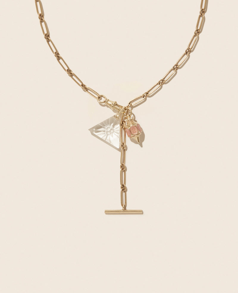 The Debbie No. 2 Necklace by Pascale Monvoisin is crafted in 9K yellow gold with a toggle clasp, featuring a clear prism-shaped crystal and pink rose pendants, elegantly displayed on a light cream background.