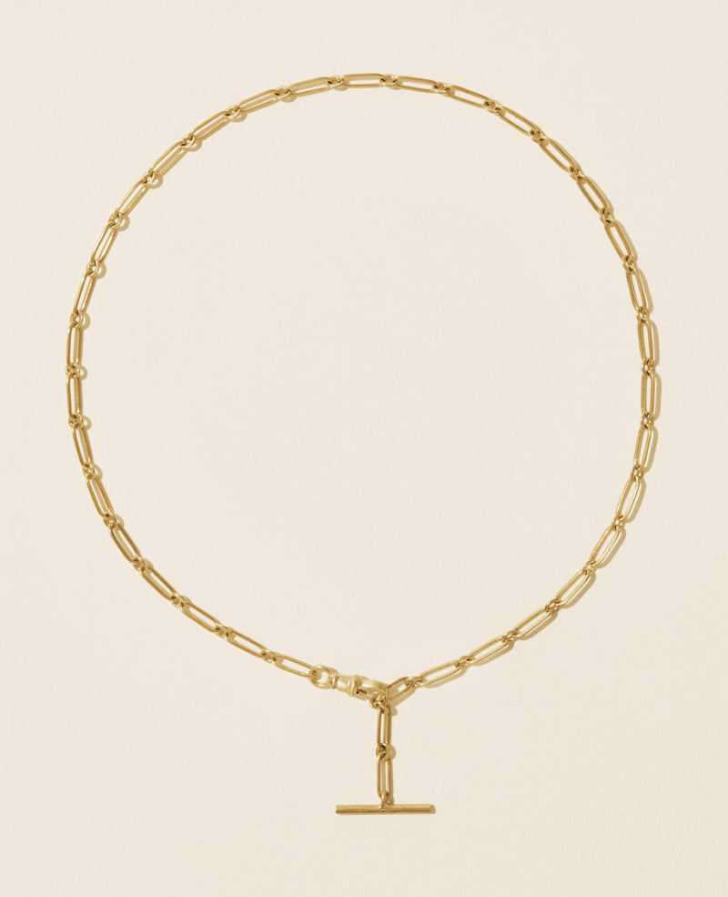 The Debbie No. 2 Necklace by Pascale Monvoisin showcases 9K yellow gold and oval links with a T-bar clasp, elegantly arranged in a circular shape against a beige background.