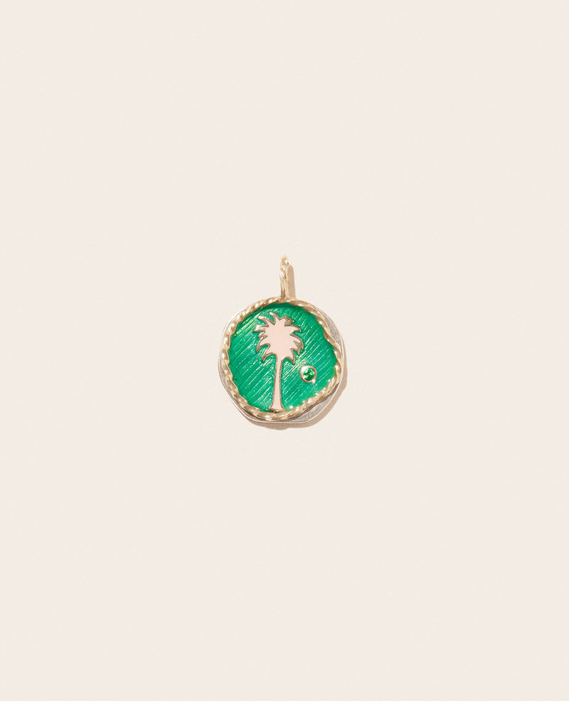 The Pascale Monvoisin Faro Green Pendant features a yellow gold palm tree design with a Tsavorite gem on the right side, set against a green enamel background and shown on a plain, light-colored backdrop.