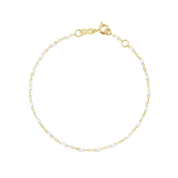The Classic Gigi Bracelet by Gigi Clozeau, available in multiple colors, showcases petite white pearls evenly distributed along its 18k gold length. Handcrafted in France, the bracelet is designed with a clasp and a small extender for an adjustable fit, set against a simple white background.