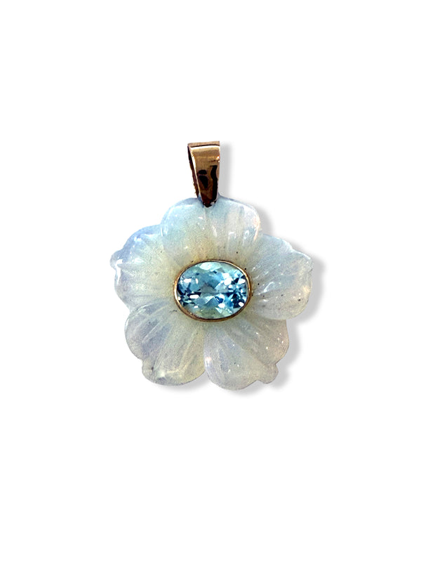 The Opal Flora pendant by Jen Proudman features a carved opalite flower with a blue topaz center and a 14k gold-toned bail, perfect for adding to your favorite necklace.
