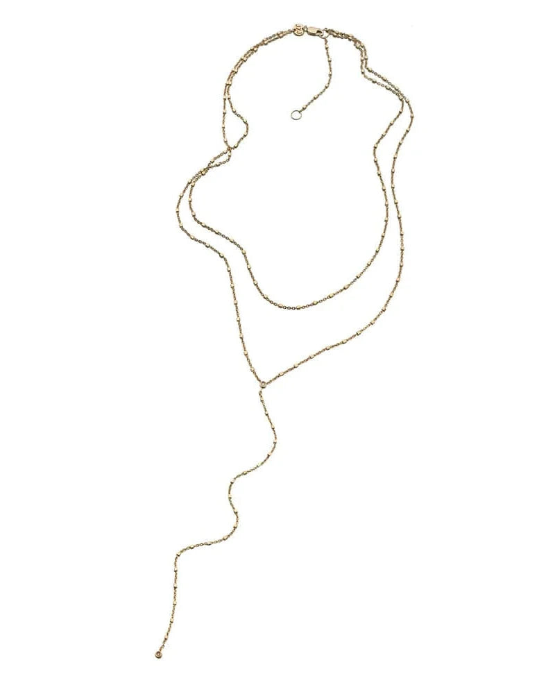 The Ace Lariat by Jennifer Zeuner is a long, delicate gold vermeil necklace featuring small, evenly spaced beads, shown loosely coiled and extended on a plain white background.