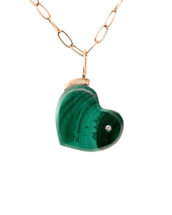 The Malachite Heart by Karen Luvaas is a gold chain necklace with a green malachite heart-shaped pendant and a small diamond embedded on the right side, displayed against a white background.