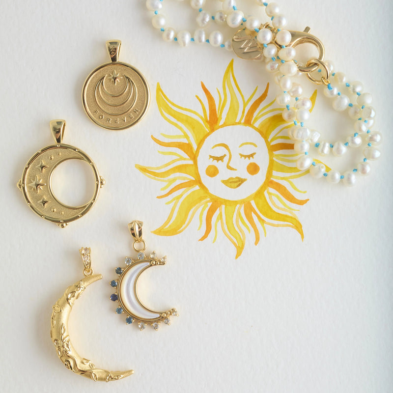 The Jane Win Mermaids Gift Pearl Necklace is displayed on white paper with a hand-painted yellow sun, featuring celestial-inspired details of stars and moons for a whimsical, sun-and-moon-themed look.
