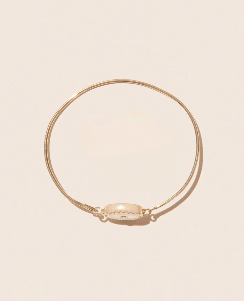 Against a plain beige background, the Bracelet ORSO MOONSTONE by Pascale Monvoisin is elegantly displayed. Featuring a circular, textured centerpiece, this bracelet is crafted in sleek yellow gold and exudes a minimalist design that captures both timelessness and elegance.